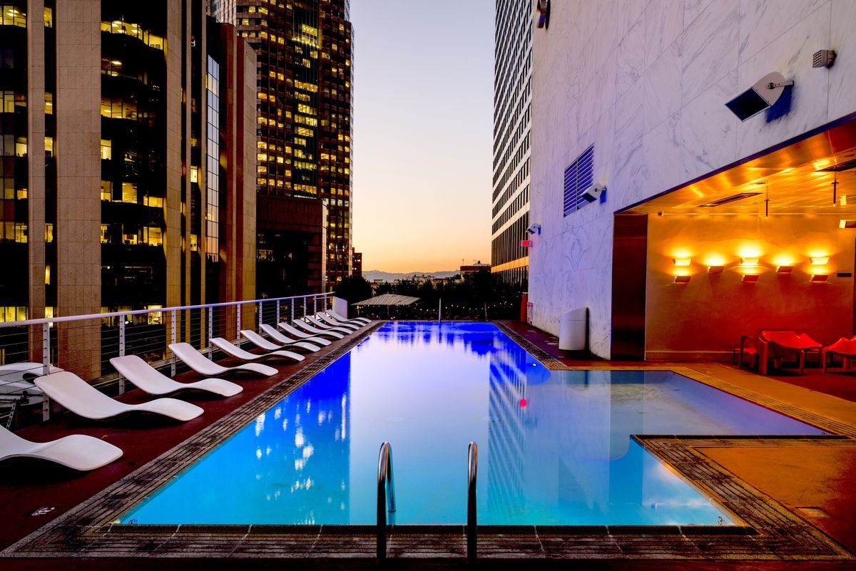 Piscine éclairée de nuit sur un rooftop urbain